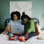 a woman sitting on a bed using a laptop